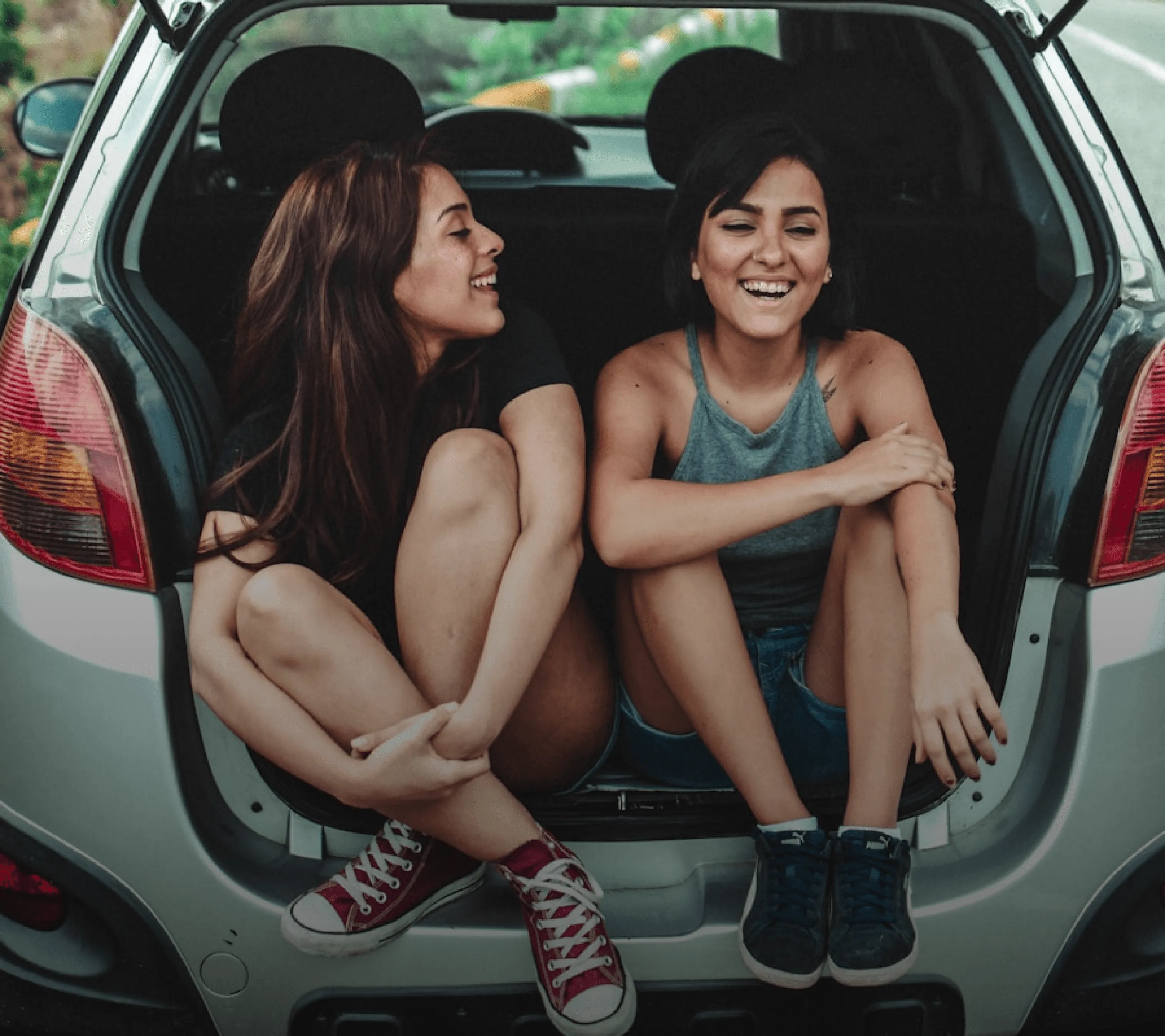 Zwei junge Frauen sitzen im Kofferraum eines Autos